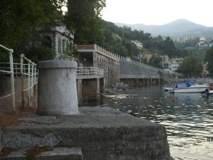 most nad rzeką z łodzią w wodzie w obiekcie Apartment Vesna A2 w mieście Ika