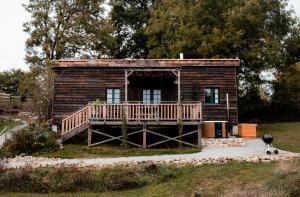 eine Blockhütte mit einer Veranda und einer Terrasse in der Unterkunft La ferme du pont de Maumy, cabane au bord de l'étang et bain nordique in Busserolles