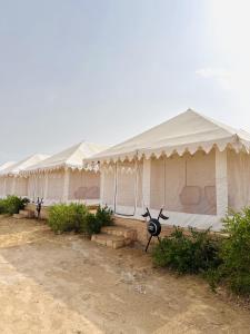een rij witte tenten geparkeerd in een veld bij Mughal Sam Sand Dunes Desert Safari in Sām