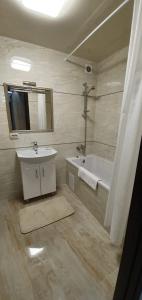 a bathroom with a sink and a tub and a mirror at Затишна квартира біля парку Відродження in Ternopilʼ