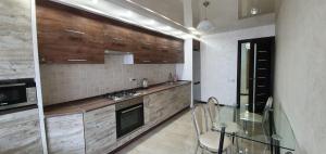 a kitchen with wooden cabinets and a glass table at Затишна квартира біля парку Відродження in Ternopilʼ +4 photos