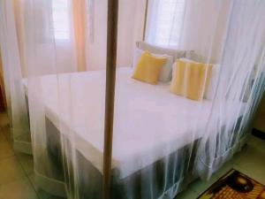un letto bianco con due cuscini gialli sopra di Vera comfort a Mombasa