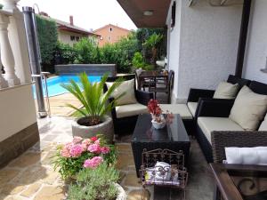 eine Terrasse mit Sofas und Pflanzen sowie einem Pool in der Unterkunft Apartments Butinar Pri Kapitanu in Ankaran