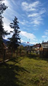 Ein Zaun auf einem Feld mit einem Baum und Bergen in der Unterkunft Beso's in Mestia