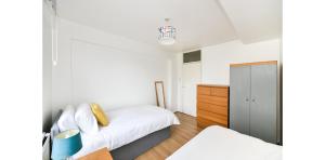 a white bedroom with a bed and a cabinet at Entire Two Bedroom Flat in the heart of Greater London in London