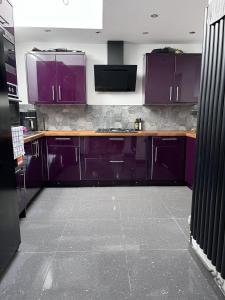 a kitchen with purple cabinets and a tile floor at Modern Newly Renovated 3 Story House in Ebbw Vale in Ebbw Vale