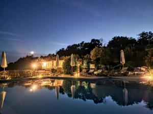 a swimming pool with chairs and umbrellas at night at Agriturismo Rosa Antica in Monte San Vito