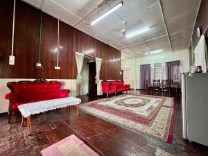 a living room with red couches and a rug at Traditional 4-bedroom Kampung House in Kota Bharu in Kampong Kebun Tok Salim