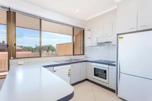 eine Küche mit weißen Geräten und einem großen Fenster in der Unterkunft Tuggeranong Short Stay #06C - Sleeps 6 in Canberra