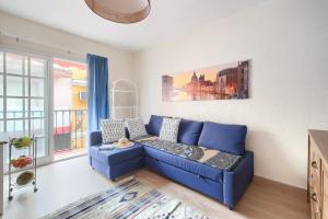 a blue couch in a living room with a window at Patio Andaluz a 100 metros de la playa in Fuengirola