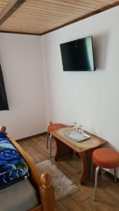 Habitación con mesa y TV en la pared. en CABANA CLAUDIA en Petroşani