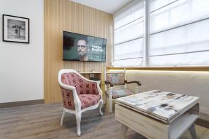 uma sala de estar com uma televisão, uma cadeira e uma mesa em Peixe Frito Apartment em Pontevedra
