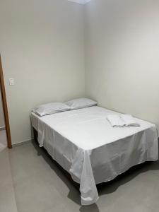een bed in een witte kamer met witte lakens bij Casa da mãe Aparecida. in Pindamonhangaba