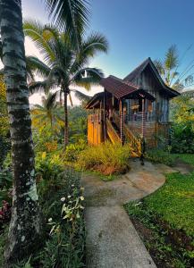 a small house with a porch and a palm tree at Jungle Haven Bali - Eco Lodge in Meliling