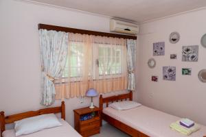 2 łóżka pojedyncze w pokoju z oknem w obiekcie Liakos' Apartments w mieście Vasilika