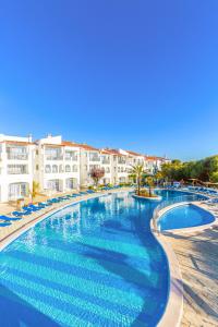 een groot zwembad met blauw water in een resort bij Vibra Caleta Playa Apartmentos-3SUP in Sa Caleta