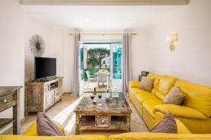 uma sala de estar com um sofá amarelo e uma mesa em Falésia Cliff Apartment by The Portuguese Butler em Albufeira
