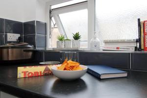 un tazón de patatas fritas y un libro en un mostrador de cocina en Cardiff Private Double Room with Shared Bathroom Wi-Fi And Free On-Street Parking, en Cardiff