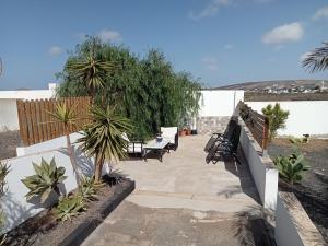un patio con bancos, palmeras y una valla en Quintero Suites, en San Bartolomé