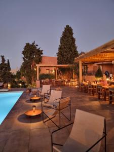 a patio with chairs and tables and a pool at Koutouloufari Village Holiday Club in Hersonissos