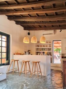 a kitchen with three stools and a counter with three lights at Koutouloufari Village Holiday Club in Hersonissos