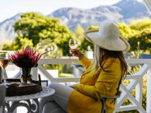 uma mulher sentada à mesa com um copo de vinho em Fleur du Soleil Luxury Guesthouse em Franschhoek