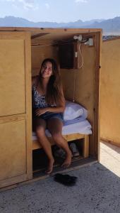 a woman sitting on a bunk bed in a room at Nautilus Capsules in Dahab