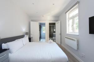 a white bedroom with a large bed and a window at Fab garden flat central Camden in London