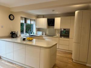 a kitchen with white cabinets and a clock on the wall at Forest Edge in Woodford Green