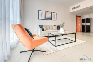 salon z pomarańczowym krzesłem i stołem w obiekcie Serene 1BR at Park Terrace Silicon Oasis by Deluxe Holiday Homes w Dubaju