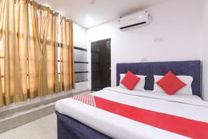 Hotel Metro Regency في لاكناو: غرفة نوم بسرير كبير ومخدات حمراء