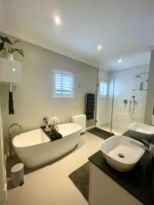 a bathroom with a large tub and a sink and a tub at Atlantic Cove in Cape Town