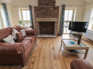 een woonkamer met een bank en een open haard bij Whinny Cottage in Alnwick