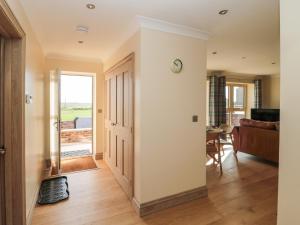 a hallway with a door and a living room at Byre Cottage in Alnwick