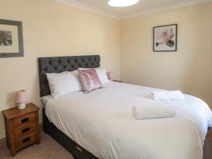 a bedroom with a large white bed and a night stand at Smithy Cottage in Alnwick +28 photos