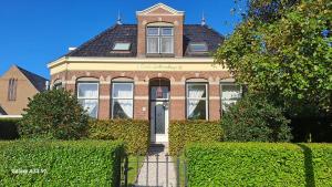 a brick house with bushes in front of it at B&B Het Oude Doktershuys in Minnertsga