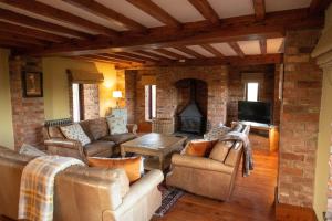 a living room with leather furniture and a brick wall at The Threshing Barn in Woodhall Spa