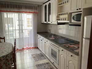 een keuken met witte kasten, een wastafel en een raam bij Vivienda de uso turistico in Ribadavia