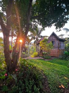 a house with the sun setting behind a tree at JungleHavenBali - Private Nature Stay in Meliling