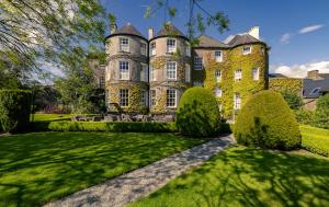 una casa grande con un patio verde con arbustos en Butler House, en Kilkenny