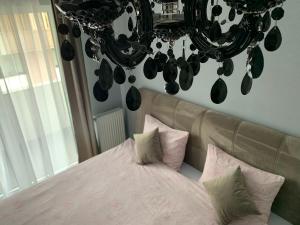 a bedroom with a pink bed and a chandelier at Tiberiu Ricci Apartament in Sibiu