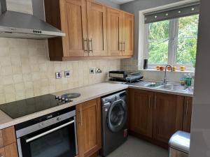 eine Küche mit Holzschränken, einer Waschmaschine und einem Trockner in der Unterkunft Grove flat - two bedroom flat in central Dunstable in Dunstable