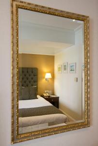 a mirror on a wall with a bed in a room at Hera Hotel in Athens