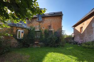 an old brick building with a yard in front of it at Au Moulin de l'Andelle in Pitres