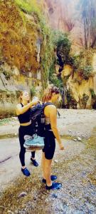dos mujeres de pie junto a una pintura de una montaña en Adventure camping - Organized Trekking from Dana to Petra, en Dana