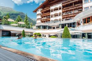 dos personas en la piscina de un hotel en Trofana Royal 5-Sterne Superior Resort en Ischgl