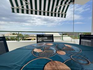 a table with a blue table cloth on a balcony at Alexandrin, superbe appt avec varangue et vue mer pour 3 personnes in Saint-Gilles les Bains