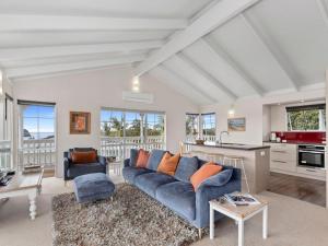 a living room with a blue couch and a kitchen at Sea Blue Heaven in Tutukaka