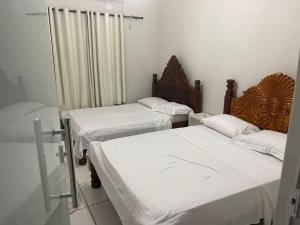 two beds in a small room with white sheets at Casa temporada no Peixe perto do rio in Peixe