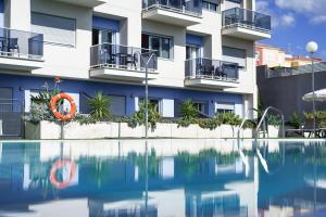 a hotel with a swimming pool in front of a building at Cornisa Apartments in Patalavaca
